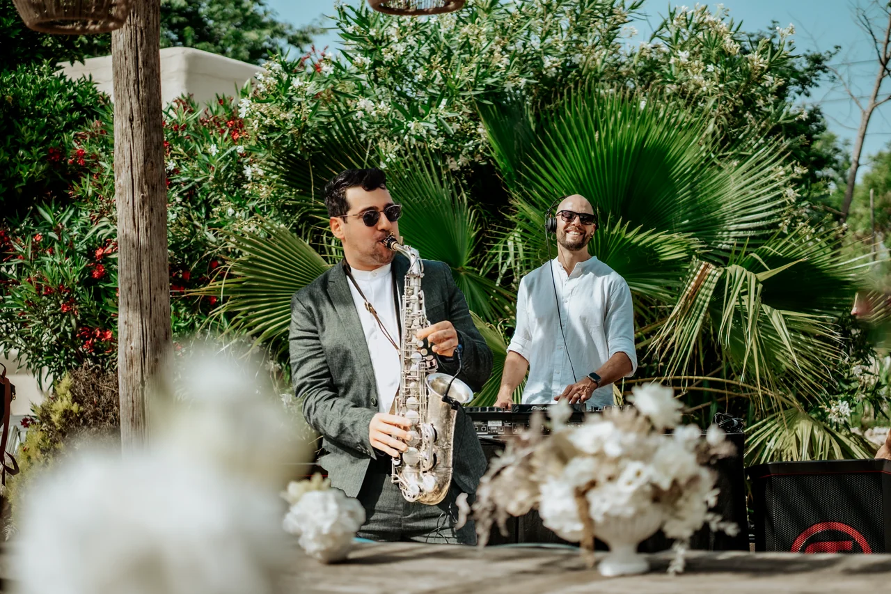 Ein Saxofonist und ein DJ spielen gemeinsam bei einer Feier im Freien.